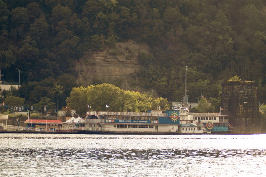 Classic riverboat docked below green cliffs in Pittsburgh